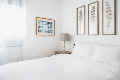 a white bedroom with a white bed and pictures on the wall at 102-1A Best Value 2BR Apt Near Central Park in New York