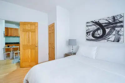 a bedroom with a white bed and a wooden door at 102-1A Best Value 2BR Apt Near Central Park in New York