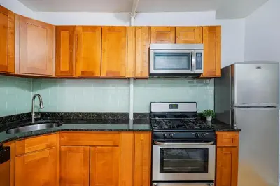 a kitchen with wooden cabinets and a stove and microwave at 102-1A Best Value 2BR Apt Near Central Park in New York