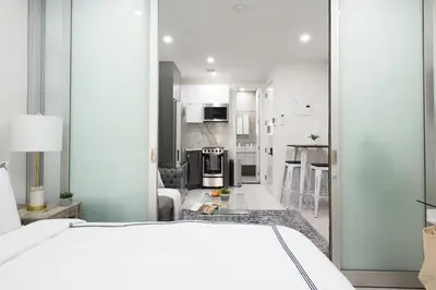 a bedroom with a white bed and a kitchen at 78-3B New Junior 1 BR Prime UES WD in unit in New York