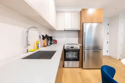 a kitchen with a stainless steel refrigerator and white cabinets at 149BK-202 NEW Condo 1BR IN PRIME GREENPOINT BK in Brooklyn