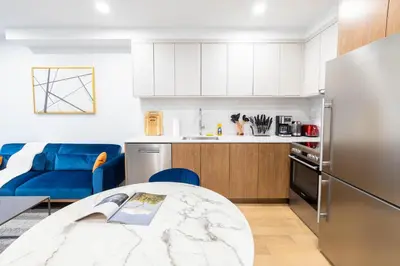 a kitchen and living room with a table and a refrigerator at 149BK-202 NEW Condo 1BR IN PRIME GREENPOINT BK in Brooklyn