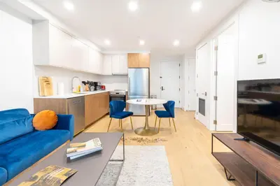 a living room with a blue couch and a kitchen at 149BK-202 NEW Condo 1BR IN PRIME GREENPOINT BK in Brooklyn