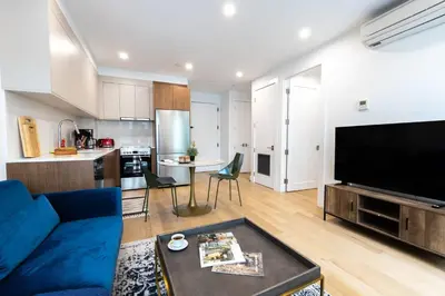 a living room with a blue couch and a kitchen at 149BK-302 New Construction 1BR WD in unit Balcony in Brooklyn