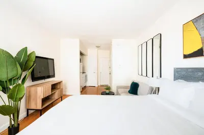 a white bedroom with a large bed and a tv at 338-3B union square Newly Reno Sleeps 3 in New York