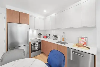 a kitchen with white cabinets and blue chairs in it at 149BK-101 New construction 2BR Private garden W-D in Brooklyn
