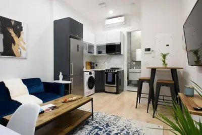 a living room with a blue couch and a kitchen at 78-4D Quality 1br W&D SKYLIGHT By Central Park in New York
