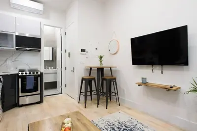 a kitchen with a table and a tv on a wall at 78-4D Quality 1br W&D SKYLIGHT By Central Park in New York