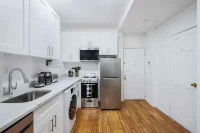 a kitchen with white cabinets and a stainless steel refrigerator at 109-1 Huge 3BR Best Value Amazing NYC Apt in New York