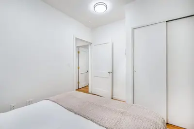 a white bedroom with a bed and a mirror at 109-1 Huge 3BR Best Value Amazing NYC Apt in New York