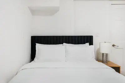 a bed with white sheets and a lamp on a table at 109-1 Huge 3BR Best Value Amazing NYC Apt in New York