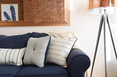 a blue couch with white pillows next to a lamp at 428-4R prime midtown large 2 BR Newly Furnished in New York
