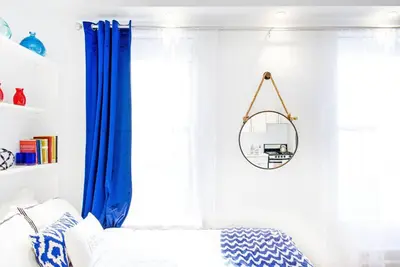 a bedroom with blue curtains and a mirror at 62-3B Studio Prime UES Walk to Central Park in New York