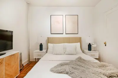 a white bedroom with a bed and a flat screen tv at 61-2A Large 1BR in Upper East Side in New York