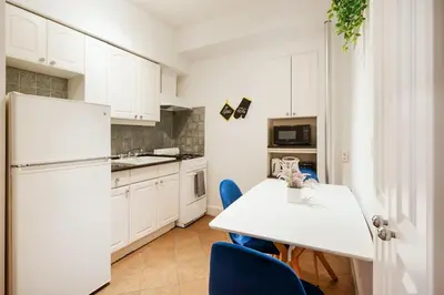 a kitchen with a white refrigerator and a table with blue chairs at 61-2A Large 1BR in Upper East Side in New York