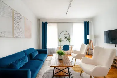 a living room with a blue couch and white chairs at 61-2A Large 1BR in Upper East Side in New York