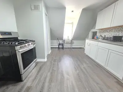 an empty kitchen with a stove and white cabinets at Room for rent in Apartment in Hartford