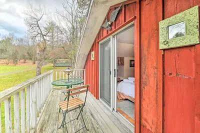 a red house with a balcony with a table and a bed at Old Time Catskill Mtn Retreat, Handcrafted Cabin! in Cornwallville