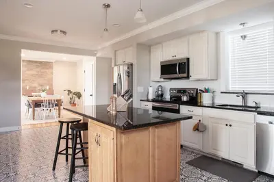 a kitchen with white cabinets and a black counter top at Farmhouse Broad Brook: Comfort & Charm. in East Windsor