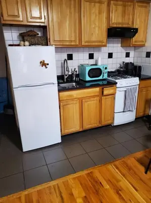 a kitchen with a white refrigerator and wooden cabinets at In the heart of nyc! Time sq, theater district, javits center in New York