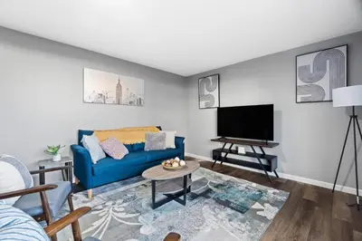 a living room with a blue couch and a flat screen tv at Lovely 3 Bedroom Colonial home in Middletown