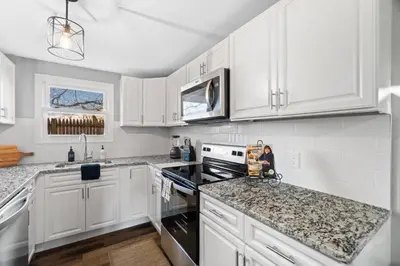 a white kitchen with white cabinets and black appliances at Lovely 3 Bedroom Colonial home in Middletown
