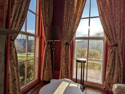 a bedroom with large windows with red walls and a bed at Cromwell Manor Inn in Cornwall-on-Hudson