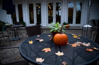 a pumpkin sitting on a table with leaves on it at Cromwell Manor Inn in Cornwall-on-Hudson