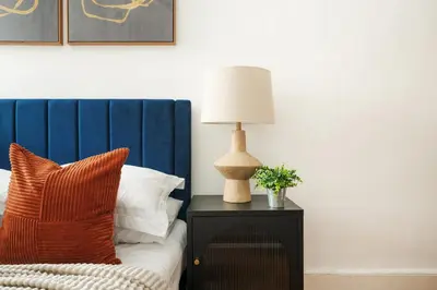 a bed with a blue headboard and a lamp on a table at 61-2C Prime UES 2BR Newly furnished best value in New York