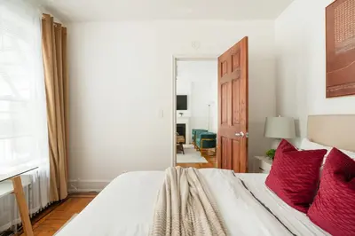 a bedroom with a bed with red pillows and a mirror at 61-2C Prime UES 2BR Newly furnished best value in New York