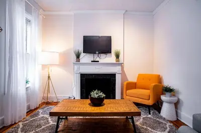 a living room with a fireplace and a tv and a chair at 61-2C Prime UES 2BR Newly furnished best value in New York