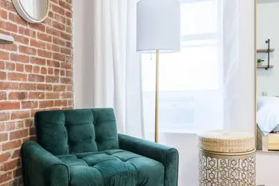a green chair in a living room with a brick wall at 454-3W PRIME location 2BR Newly Furnished sleeps 5 in New York