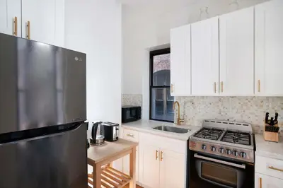 a kitchen with white cabinets and a stainless steel refrigerator at 454-4R New 2BR prime midtown Best value Sleeps 5 in New York