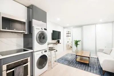a living room with a kitchen with a washer and dryer at 75-1A NEW Prime UES W D in unit Elevator in New York