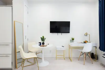 a living room with a table and chairs and a tv at 62-3A NEW Prime UES W D in unit Walk 2 C park in New York
