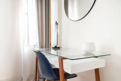 a glass desk with a blue chair and a mirror at 75-2A furnished 1BR W D Elev central park in New York