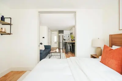 a bedroom with a white bed and a living room at 75-2A furnished 1BR W D Elev central park in New York