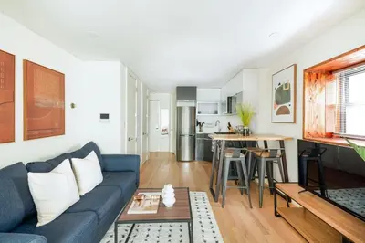 a living room with a blue couch and a kitchen at 75-2A furnished 1BR W D Elev central park in New York