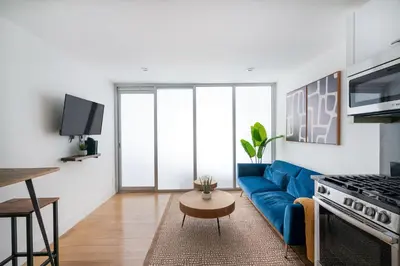 a living room with a blue couch and a kitchen at 75-2D NEW Prime UES W&D Balcony Elevator in New York