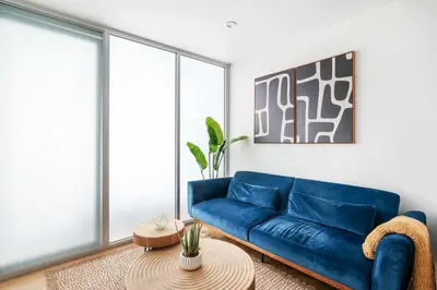 a living room with a blue couch and a table at 75-2D NEW Prime UES W&D Balcony Elevator in New York