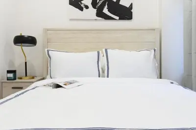 a white bed with white pillows and a black lamp at 75-3A 3Br Duplex Prime UES WD in unit Sleeps 6 in New York