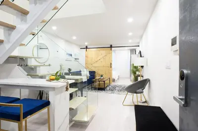 a room with a staircase and a living room with blue chairs at 75-3A 3Br Duplex Prime UES WD in unit Sleeps 6 in New York