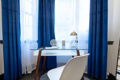 a glass table and a white chair in front of a window at E10-1 Designer East Village Townhouse 1BR in New York