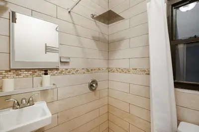 a bathroom with a shower with a sink and a mirror at 428-2W Newly Furnished Prime Location 2BR Sleeps 5 in New York
