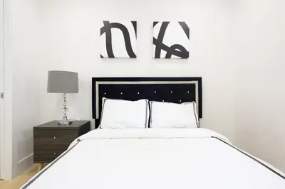 a white bedroom with a large bed and a nightstand at 75-5D NEW Quality 3BR Duplex W&D Elevator in New York