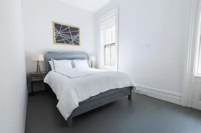 a white bedroom with a large bed and two windows at E10-2 Designer East Village Townhouse 1BR W D in New York
