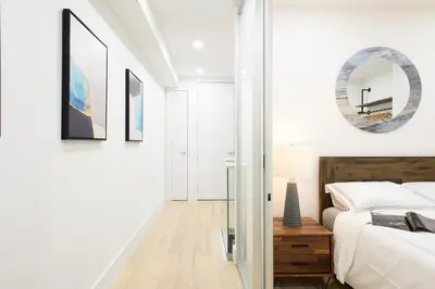 a white bedroom with a bed and a mirror at 75-5A Luxury 3BR Duplex W D in unit Elevator in New York