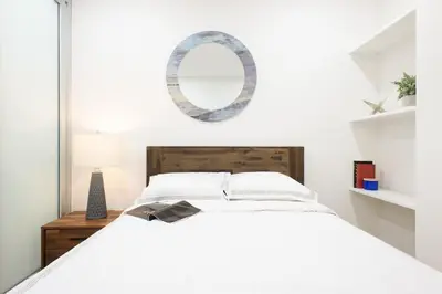 a white bedroom with a bed and a mirror at 75-5A Luxury 3BR Duplex W D in unit Elevator in New York