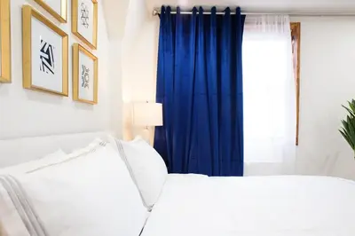 a bedroom with a white bed and blue curtains at 75-5A Luxury 3BR Duplex W D in unit Elevator in New York