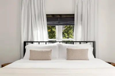 a white bed with two pillows in front of a window at Hunter Bungalow - Luxury Cabin, Kid-Friendly in Lanesville